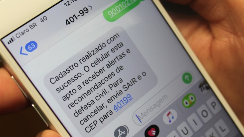Um telefone com várias palavras escritas relacionadas ao cadastramento de CEP por SMS para o recebimento de alertas da Defesa Civil