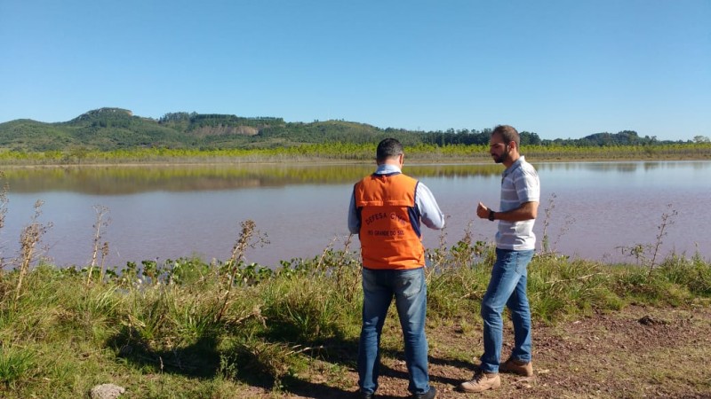 Dois homens ao lado de uma barragem conversando.