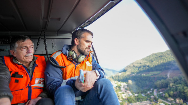 A foto mostra o governador no helicóptero vendo as áreas atingidas
